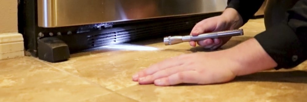 Inspecting for roaches under fridge